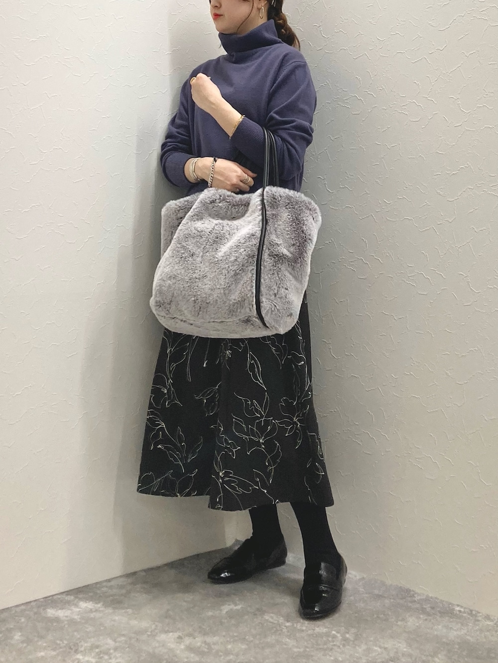 グレー系のニット/セーター、ブラック系のスカート、グレー系のトートバッグを着用したレディースの冬コーディネートの7枚目の写真