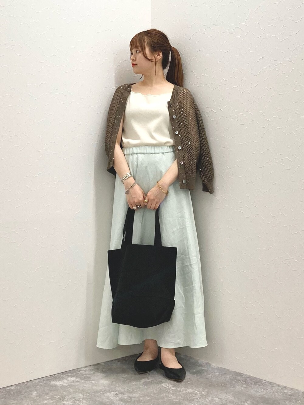 ブラウン系のカーディガン/ボレロ、グリーン系のスカート、ブラック系のショルダーバッグを着用したレディースの春コーディネートの8枚目の写真