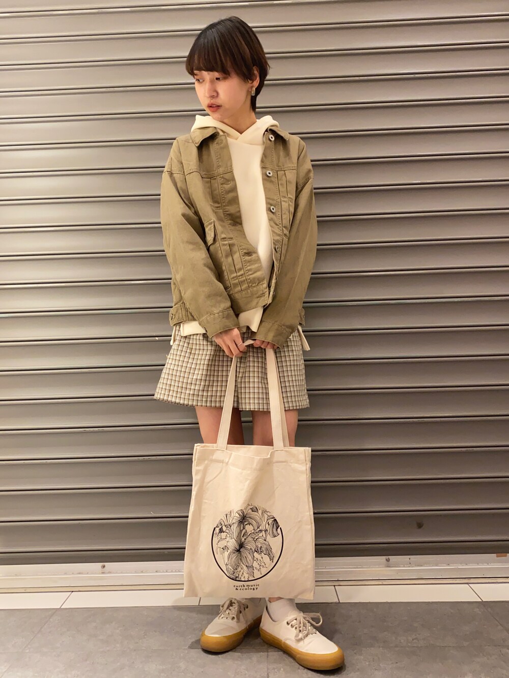 ホワイト系のトートバッグ、ブラウン系のデニムジャケット、ブルー系のトップスを着用したレディースの春コーディネートの3枚目の写真