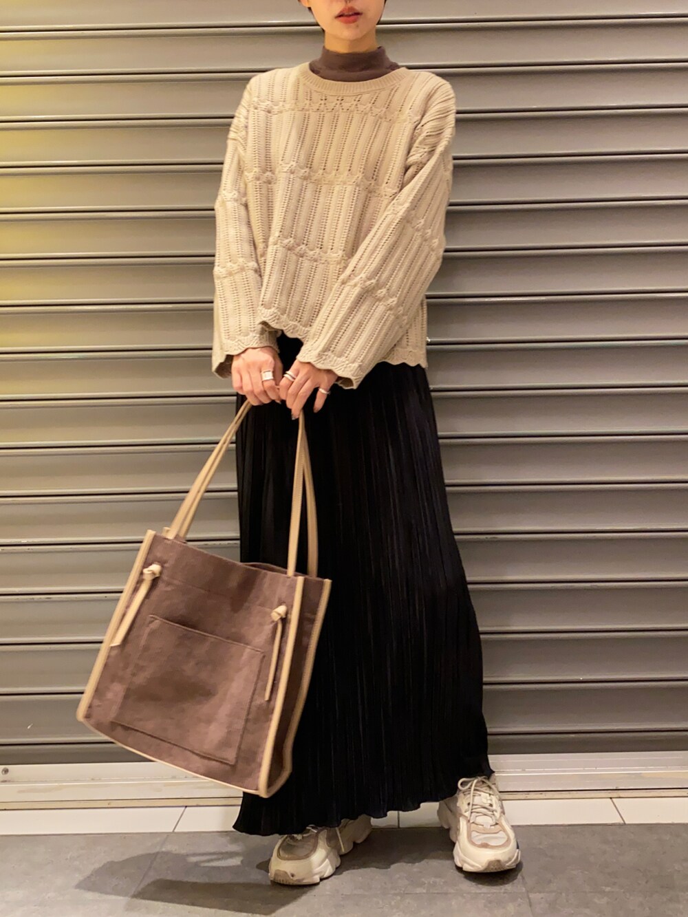 ベージュ系のニット/セーター、ブラウン系のTシャツ/カットソー、ブラック系のスカートを着用したレディースの秋コーディネートの2枚目の写真