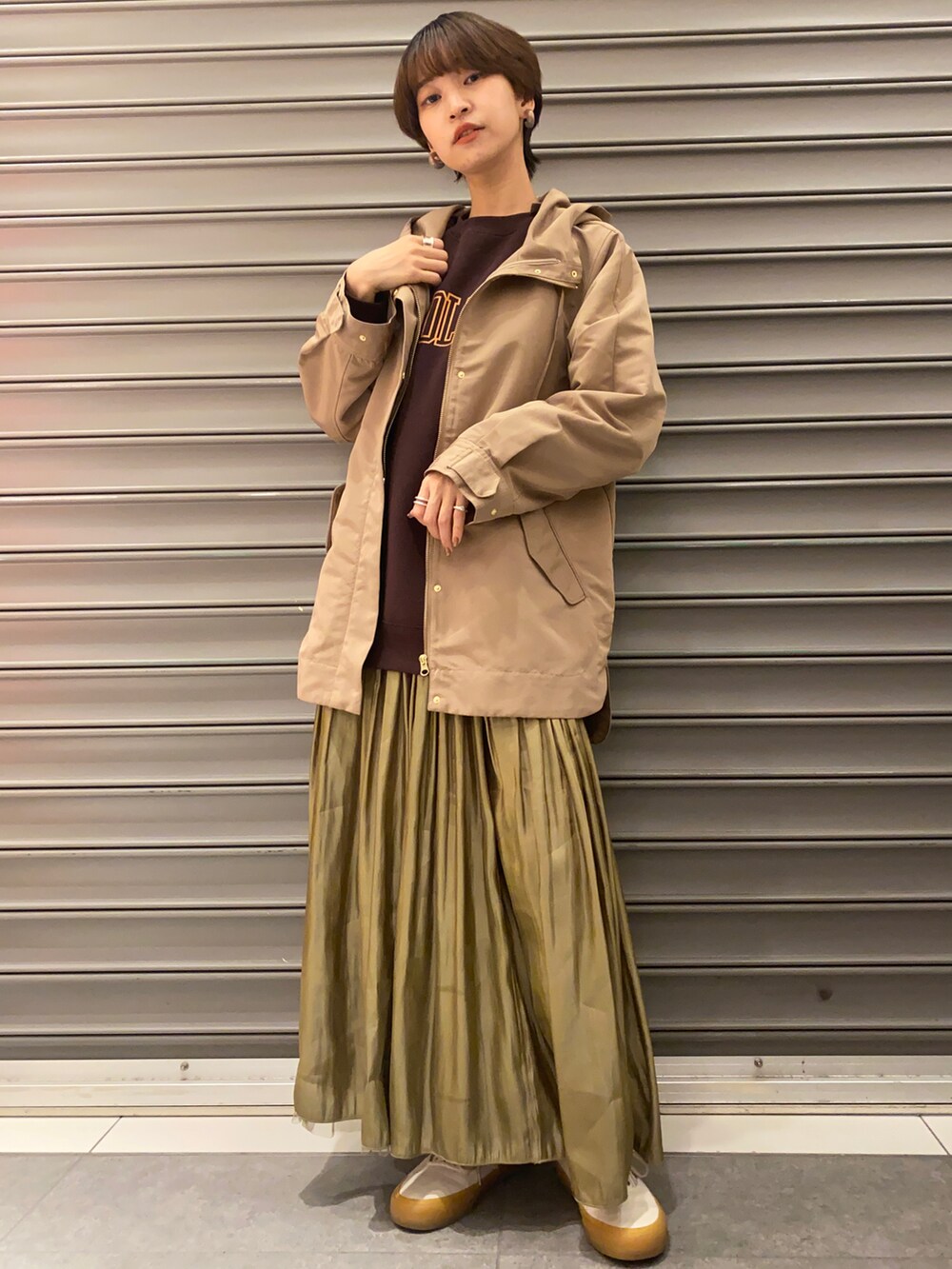 ブラウン系のTシャツ/カットソー、ベージュ系のマウンテンパーカー、イエロー系のスカートを着用したレディースの冬コーディネートの3枚目の写真