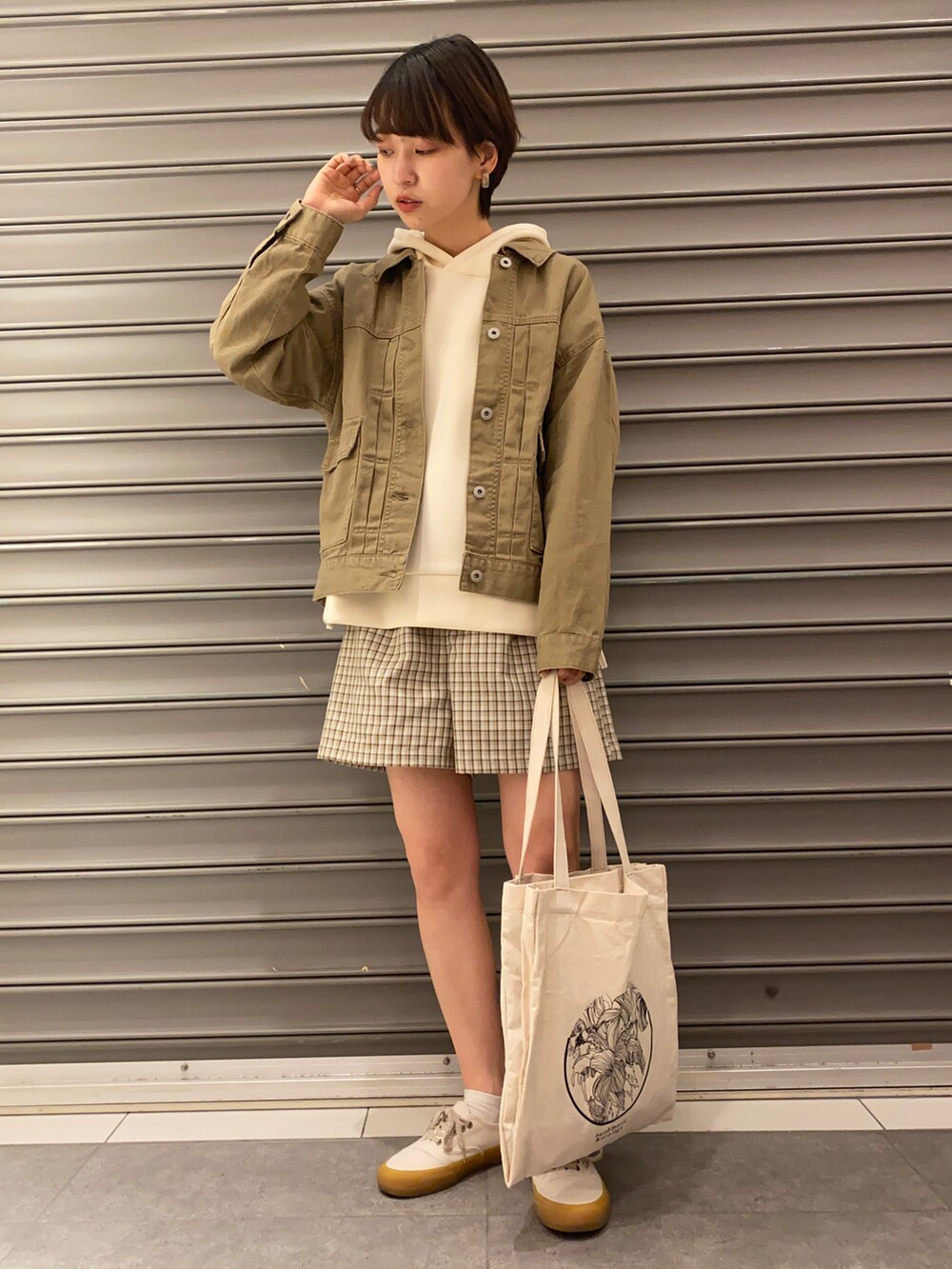 ホワイト系のトートバッグ、ブラウン系のデニムジャケット、ブルー系のトップスを着用したレディースの春コーディネートの2枚目の写真