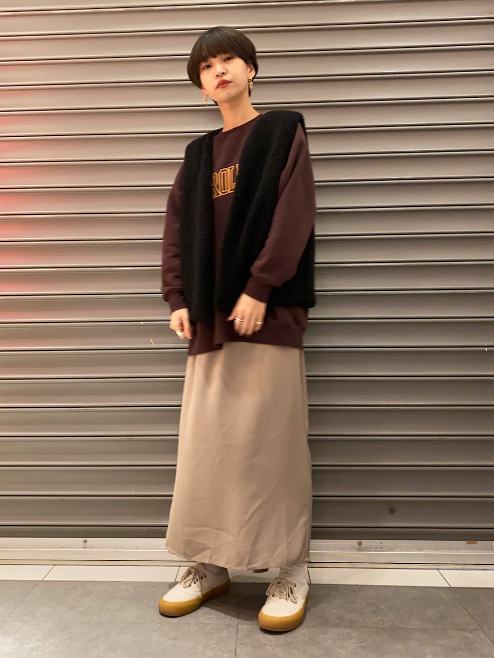 ブラック系のベスト、ブラウン系のTシャツ/カットソー、ベージュ系のスカートを着用したレディースの冬コーディネートの2枚目の写真