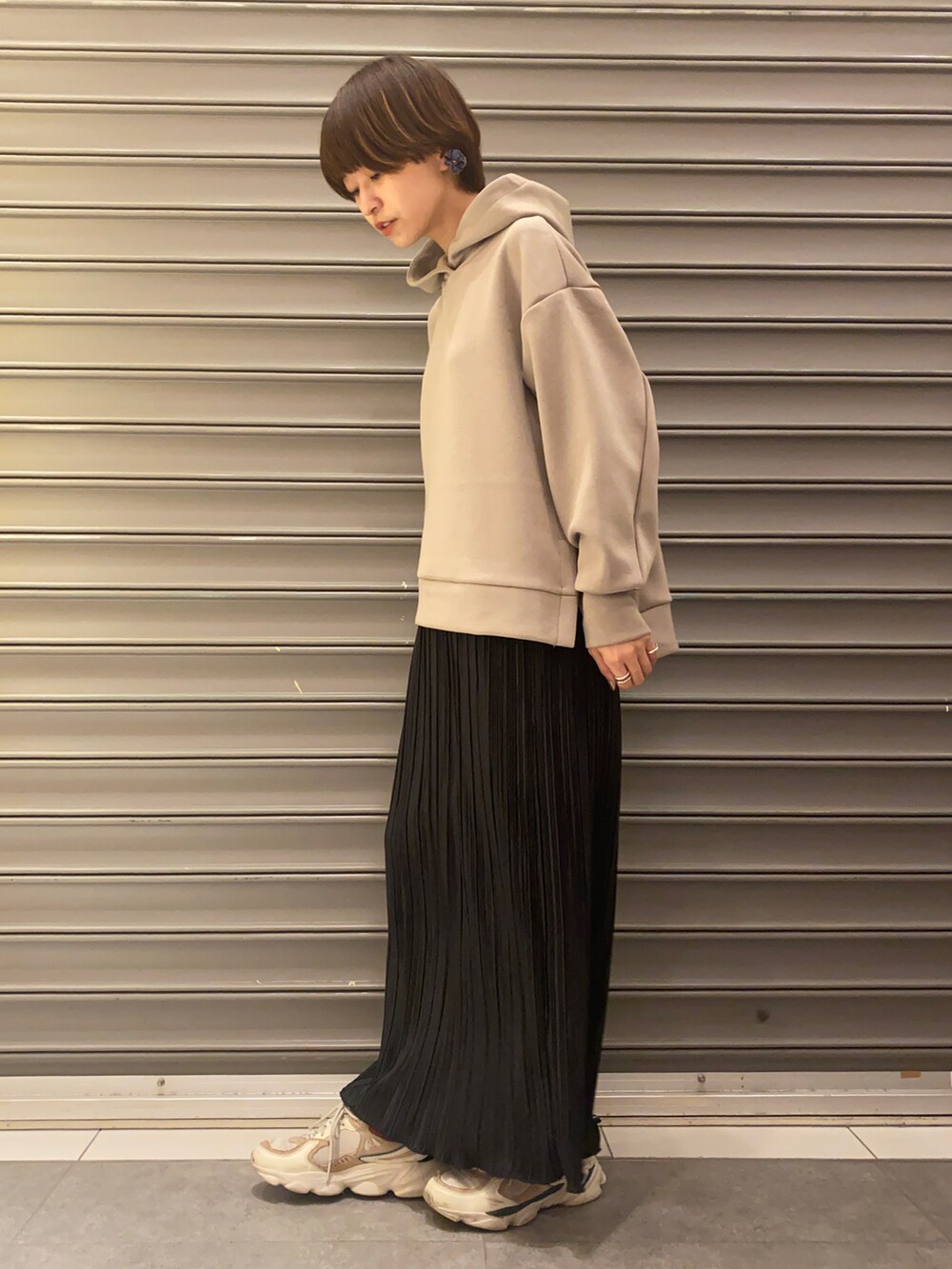 ホワイト系のスニーカー、ブラック系のスカート、ベージュ系のパーカーを着用したレディースの冬コーディネートの2枚目の写真
