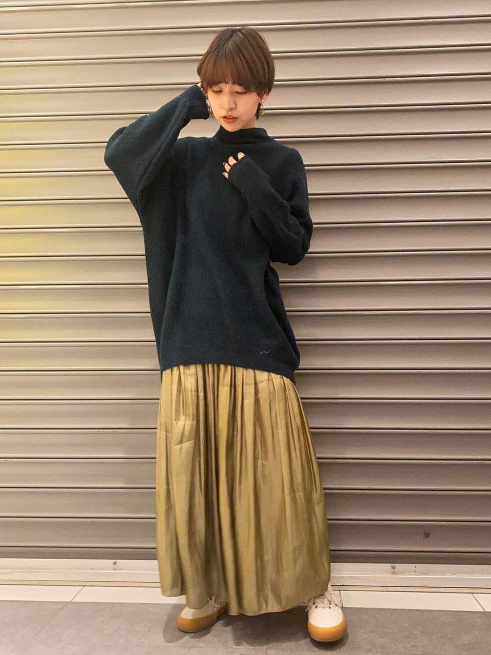 グリーン系のニット/セーター、イエロー系のスカート、ブラック系のその他アウターを着用したレディースの冬コーディネートの2枚目の写真