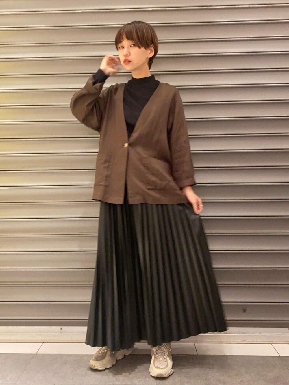 ブラウン系のノーカラージャケット、ブラック系のスカート、ブラック系のTシャツ/カットソーを着用したレディースの秋コーディネートの2枚目の写真