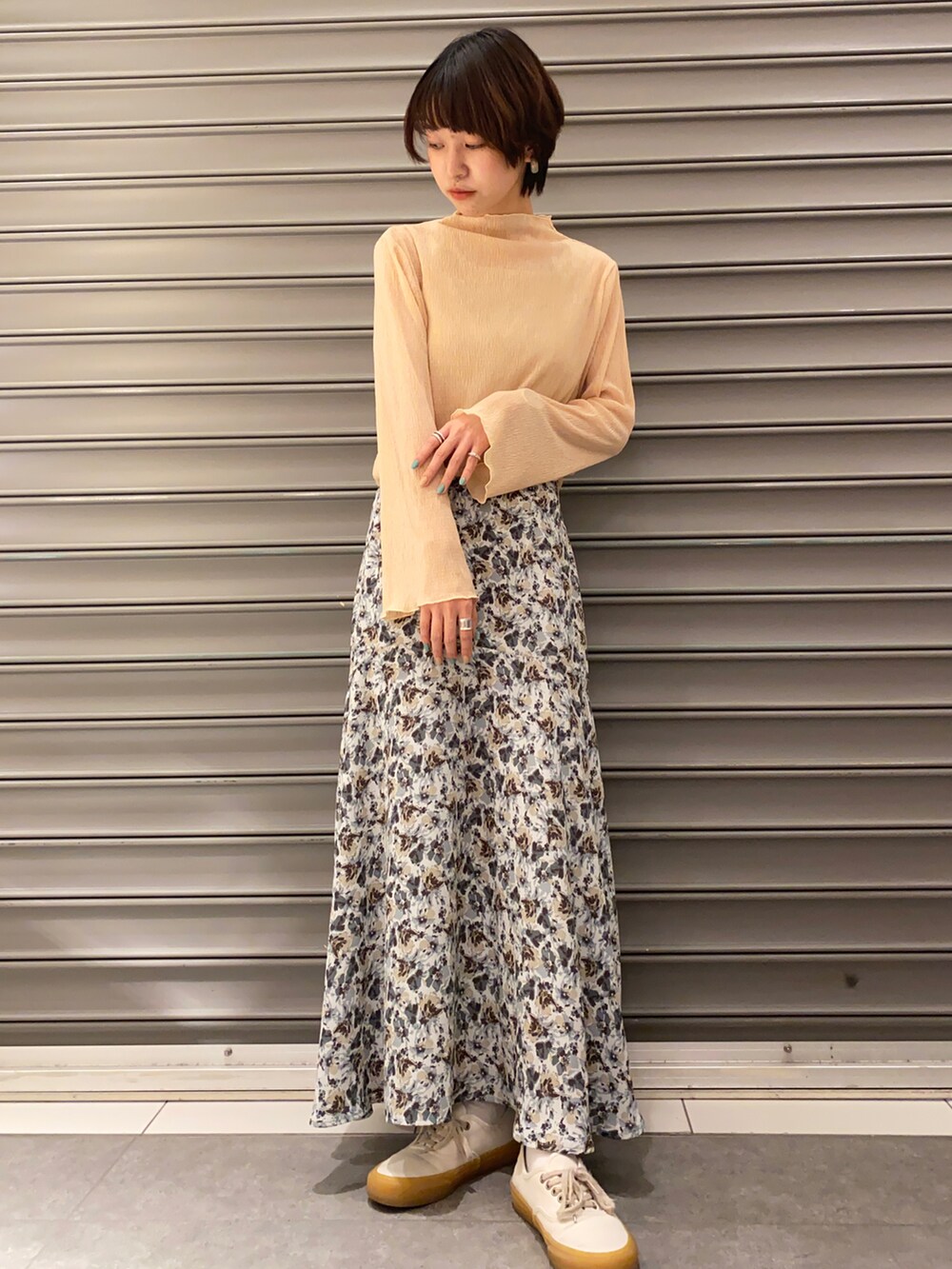 ブルー系のスカート、ホワイト系のスニーカー、ベージュ系のトレンチコートを着用したレディースの春コーディネートの3枚目の写真