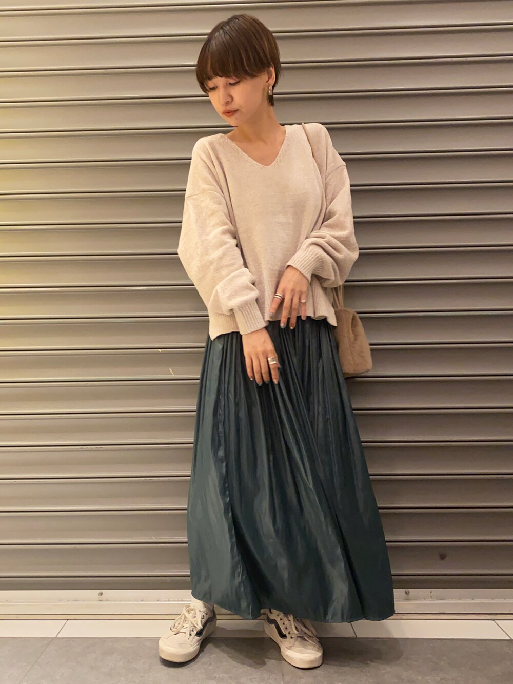 グリーン系のスカート、ブラウン系のトートバッグ、ホワイト系のニット/セーターを着用したレディースの秋コーディネートの2枚目の写真