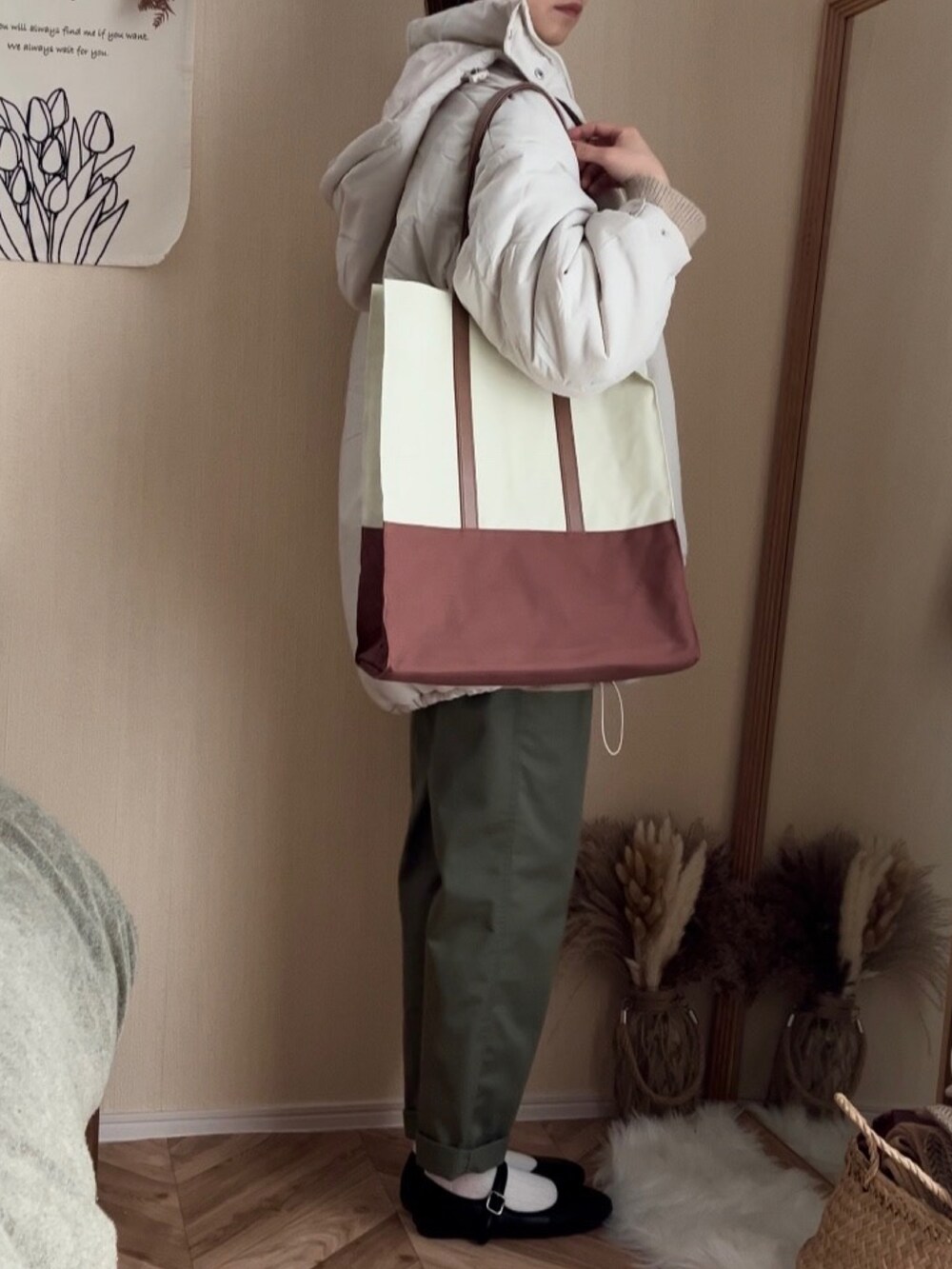 ホワイト系のダウンジャケット/コート、ベージュ系のニット/セーター、グリーン系のチノパンツを着用したレディースの冬コーディネートの2枚目の写真