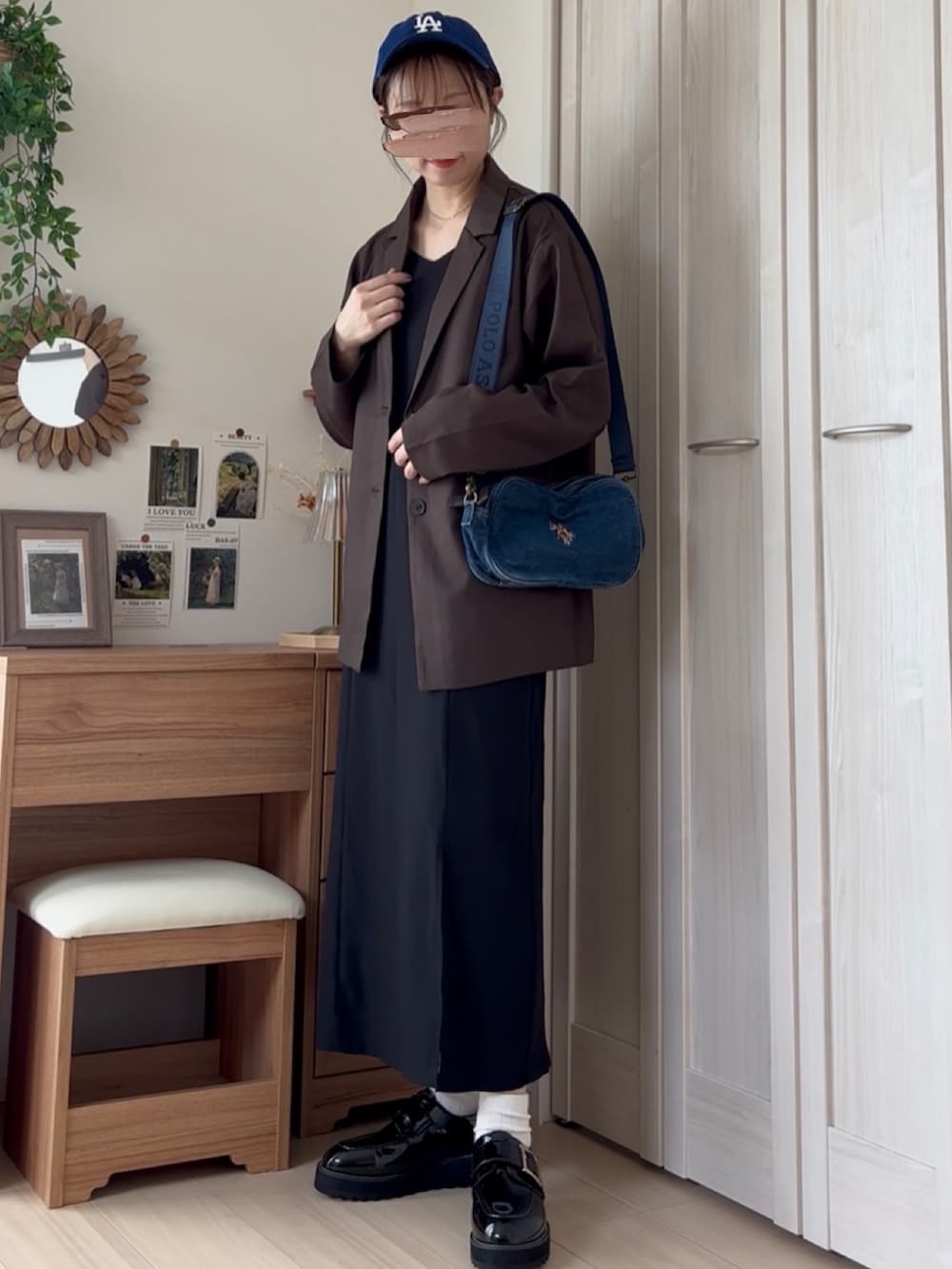 ブラウン系のテーラードジャケット、ブルー系のショルダーバッグ、ブラック系のドレスを着用したレディースの夏コーディネートの2枚目の写真