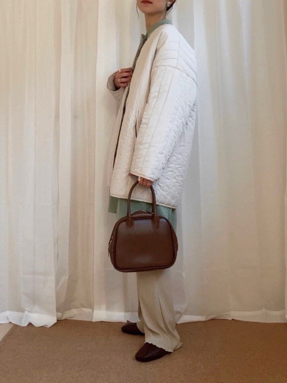 ホワイト系のノーカラーコート、グリーン系のシャツ/ブラウス、ブラック系のその他パンツを着用したレディースの冬コーディネートの2枚目の写真