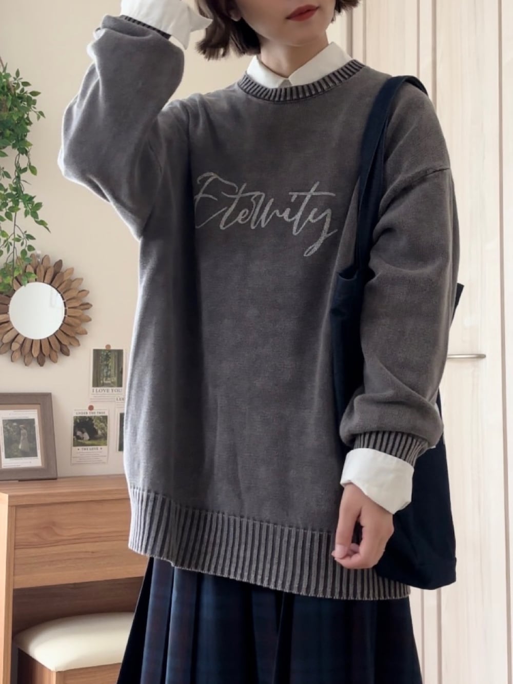 ブラック系のニット/セーター、ブルー系のスカート、ブルー系のトートバッグを着用したレディースの秋コーディネートの2枚目の写真