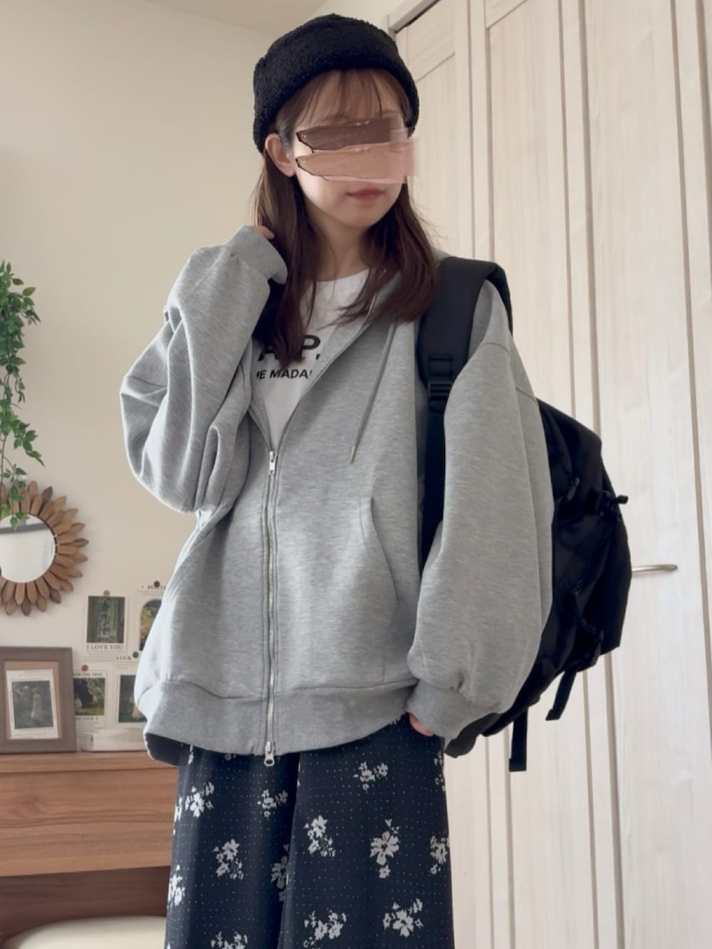グレー系のパーカー、ブラック系のスカート、ブラック系のバックパック/リュックを着用したレディースの秋コーディネートの2枚目の写真