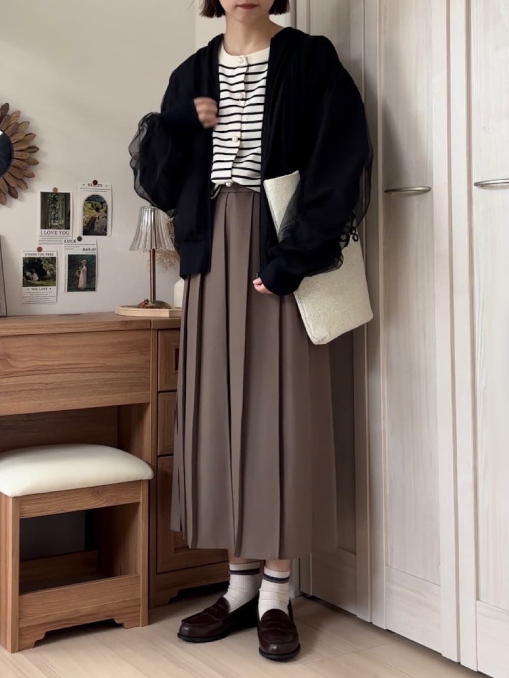 ブラック系のブルゾン、ホワイト系のカーディガン/ボレロ、ブラウン系のローファーを着用したレディースの秋コーディネートの4枚目の写真