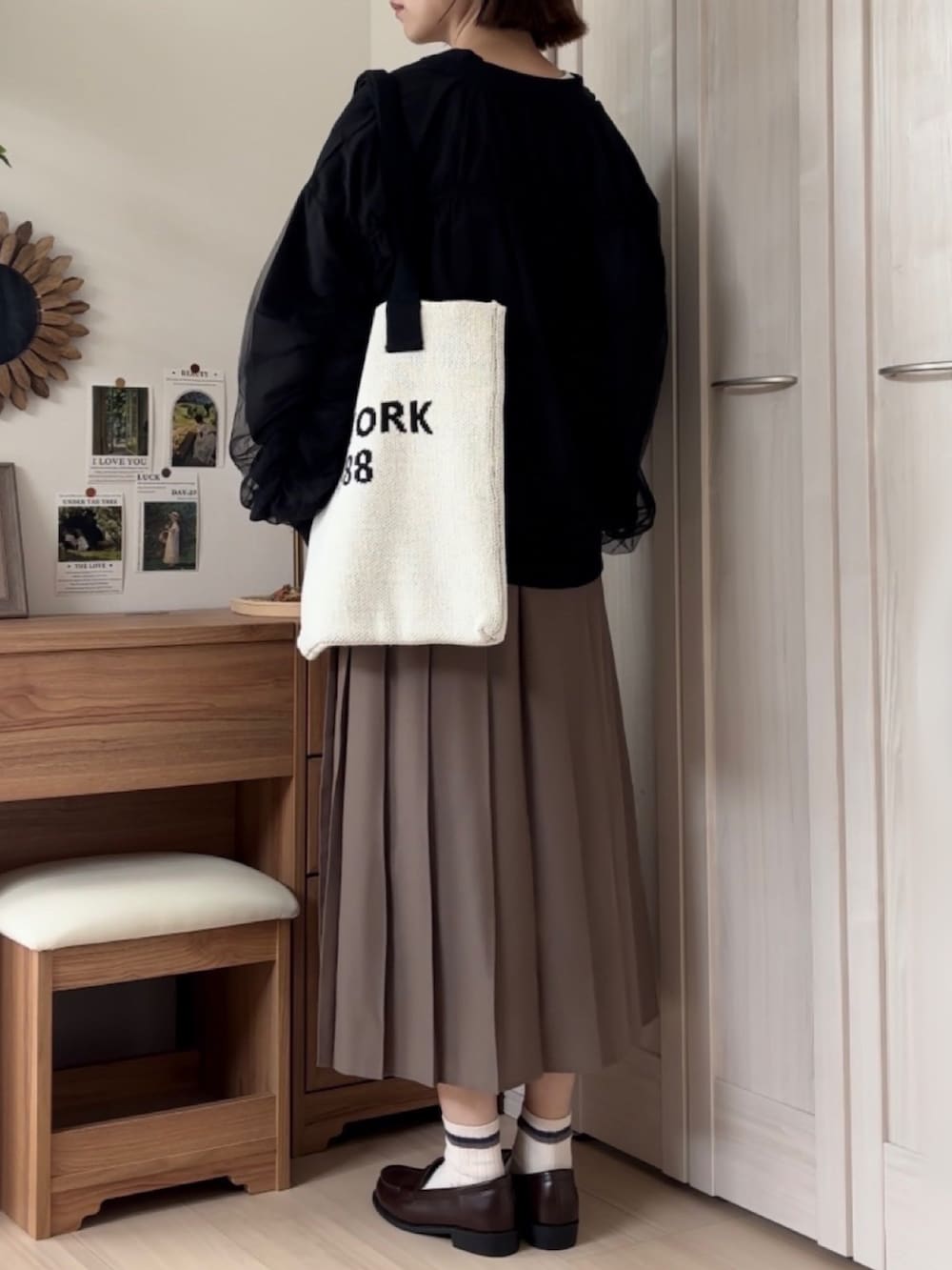 ブラック系のブルゾン、ホワイト系のカーディガン/ボレロ、ブラウン系のローファーを着用したレディースの秋コーディネートの3枚目の写真