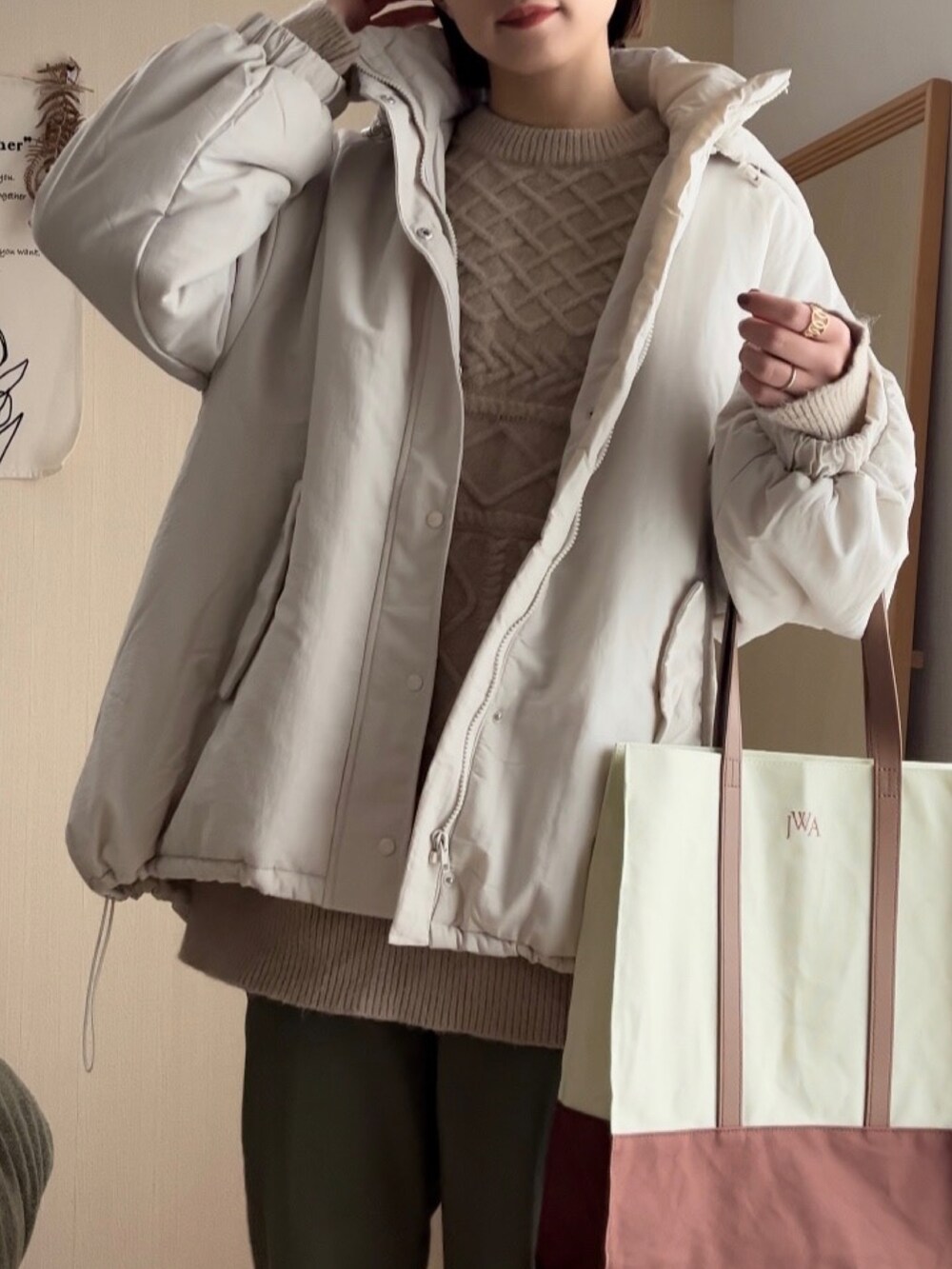 ホワイト系のダウンジャケット/コート、ベージュ系のニット/セーター、グリーン系のチノパンツを着用したレディースの冬コーディネートの3枚目の写真