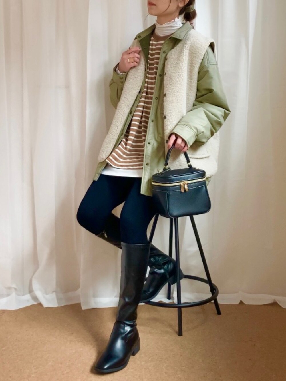 グリーン系のダウンジャケット/コート、ベージュ系のベスト、ブラウン系のTシャツ/カットソーを着用したレディースの冬コーディネートの2枚目の写真