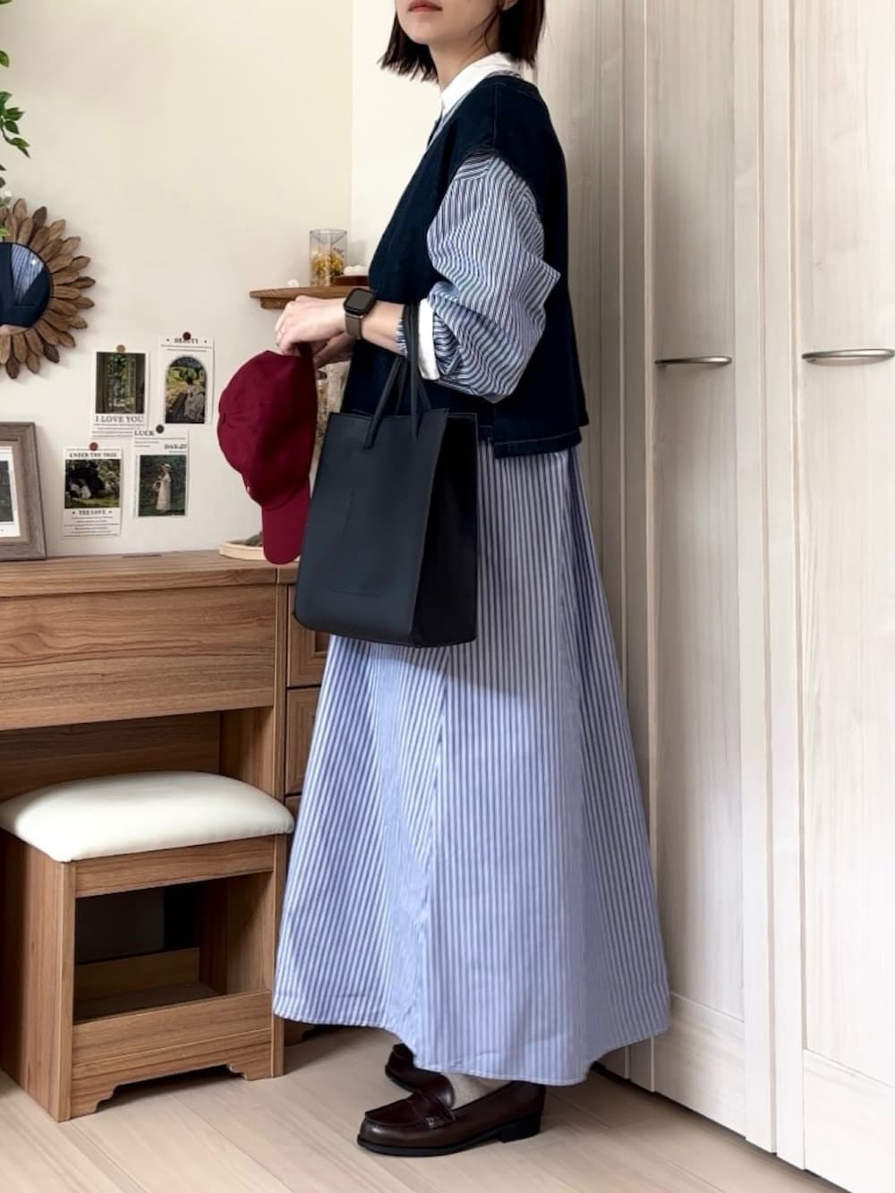 ブルー系のシャツワンピース、ブルー系のベスト、ブラック系のトートバッグを着用したレディースの春コーディネートの2枚目の写真