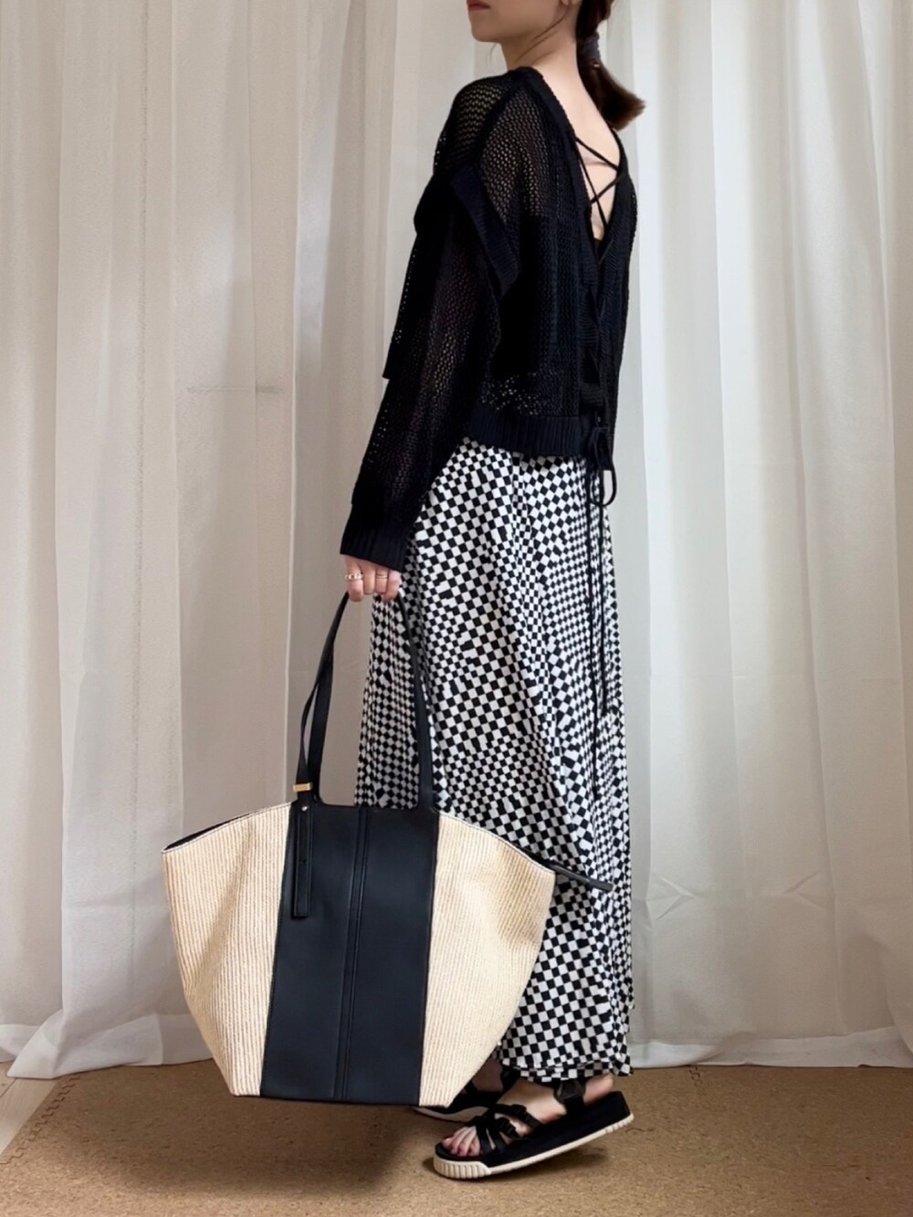 ホワイト系のスカート、ブラック系のサンダルを着用したレディースの春コーディネートの2枚目の写真