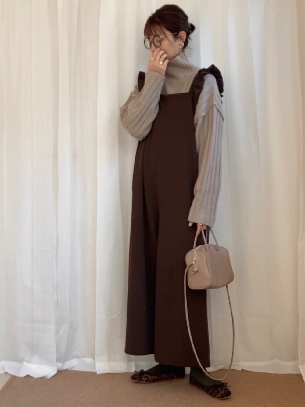 ベージュ系のニット/セーター、ブラウン系のサロペット/オーバーオール、ブラック系のパンプスを着用したレディースの冬コーディネートの2枚目の写真
