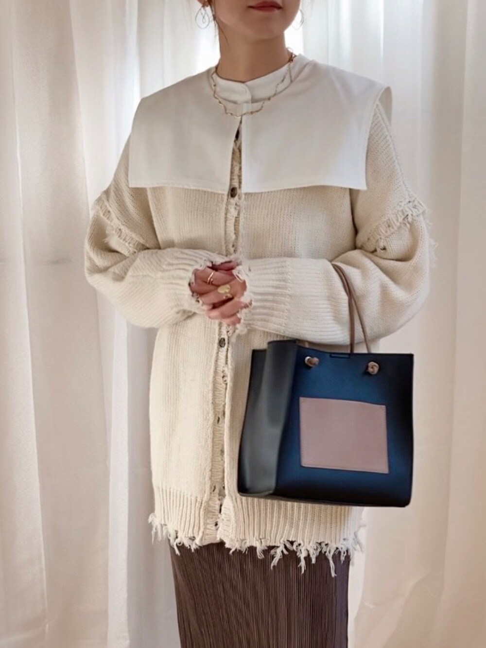 ホワイト系のニット/セーター、ホワイト系のシャツ/ブラウス、ブラウン系のスカートを着用したレディースの冬コーディネートの2枚目の写真