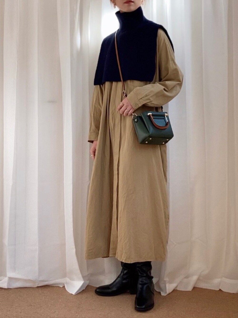 ブルー系のニット/セーター、ベージュ系のワンピース、ブラック系のブーツを着用したレディースの冬コーディネートの2枚目の写真