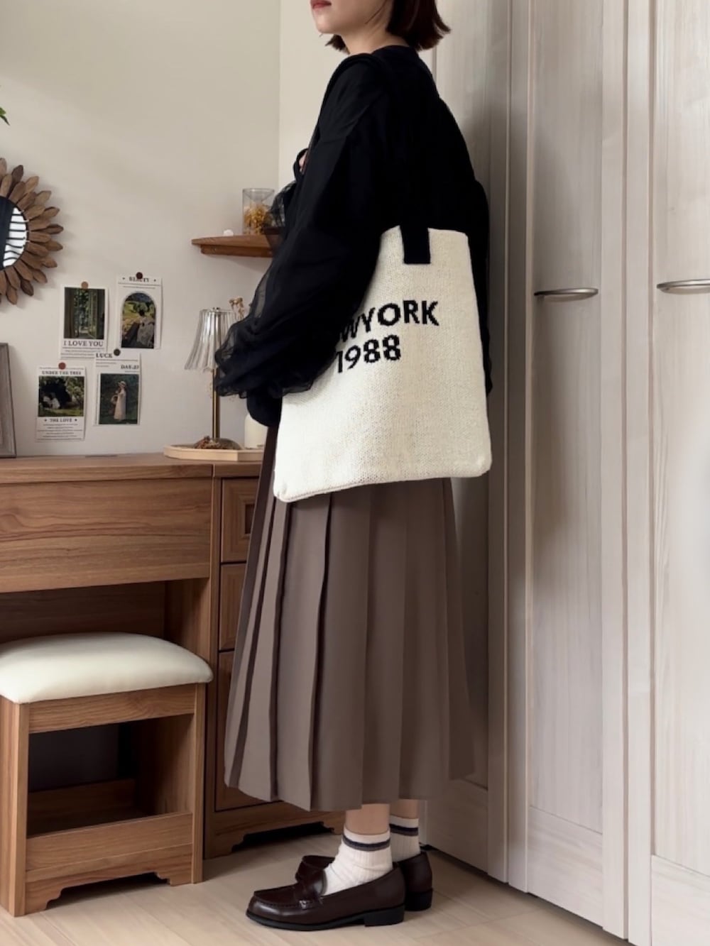 ブラック系のブルゾン、ホワイト系のカーディガン/ボレロ、ブラウン系のローファーを着用したレディースの秋コーディネートの5枚目の写真