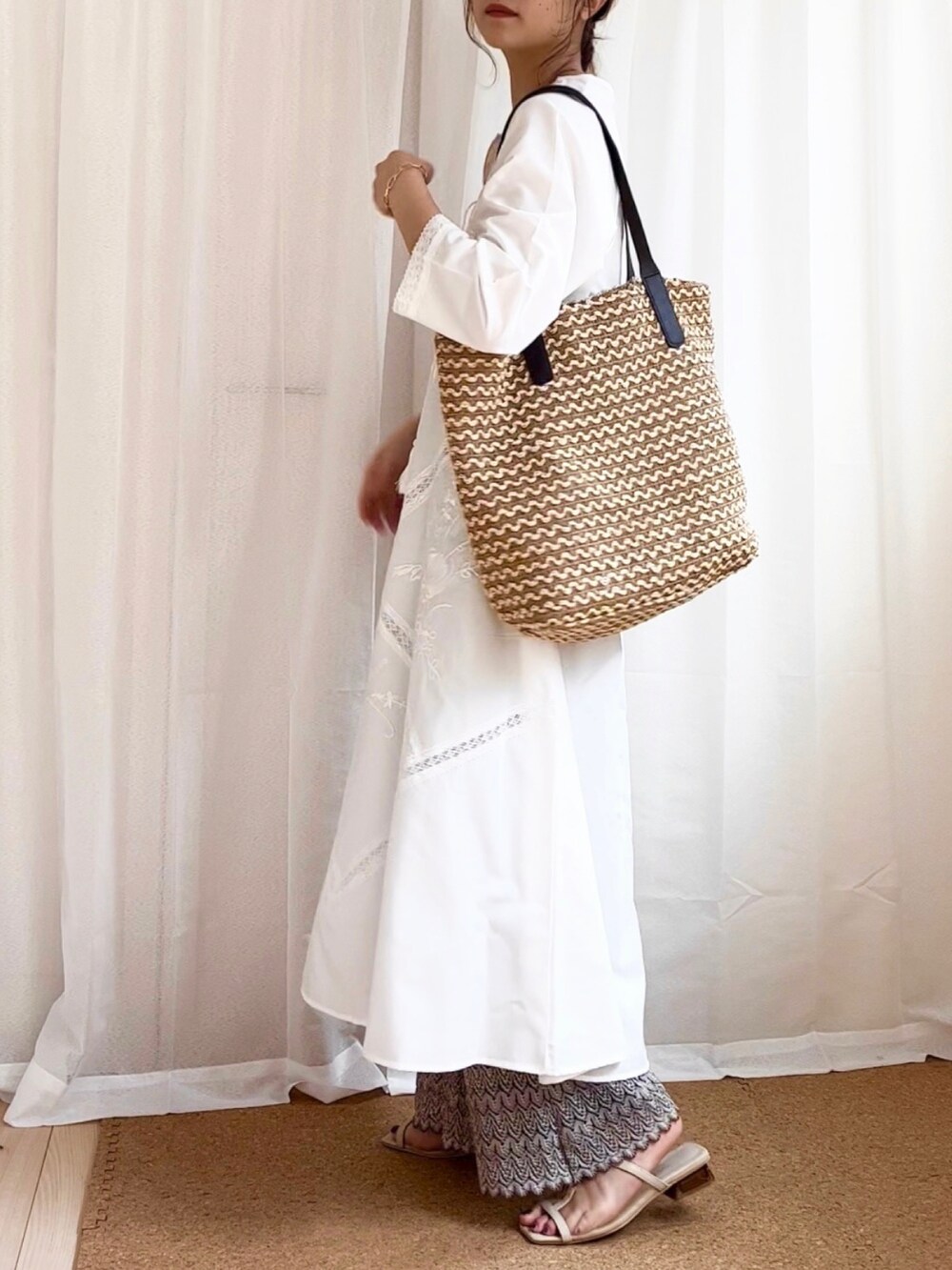 ホワイト系のワンピース、ベージュ系のかごバッグ、ベージュ系のサンダルを着用したレディースの夏コーディネートの3枚目の写真