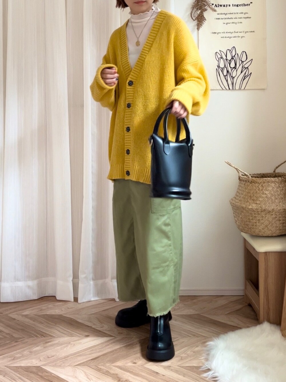 イエロー系のカーディガン/ボレロ、グリーン系のスカート、ブラック系のブーツを着用したレディースの冬コーディネートの2枚目の写真