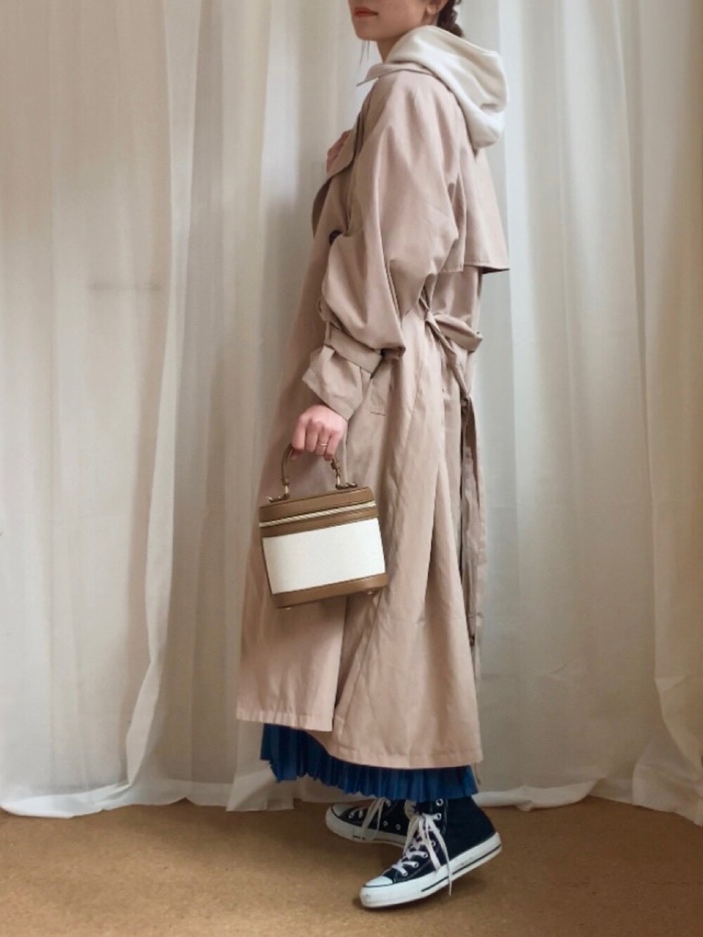 ベージュ系のトレンチコート、ホワイト系のパーカー、ブルー系のデニムスカートを着用したレディースの冬コーディネートの3枚目の写真