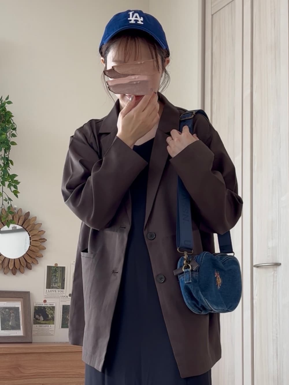 ブラウン系のテーラードジャケット、ブルー系のショルダーバッグ、ブラック系のドレスを着用したレディースの夏コーディネートの4枚目の写真