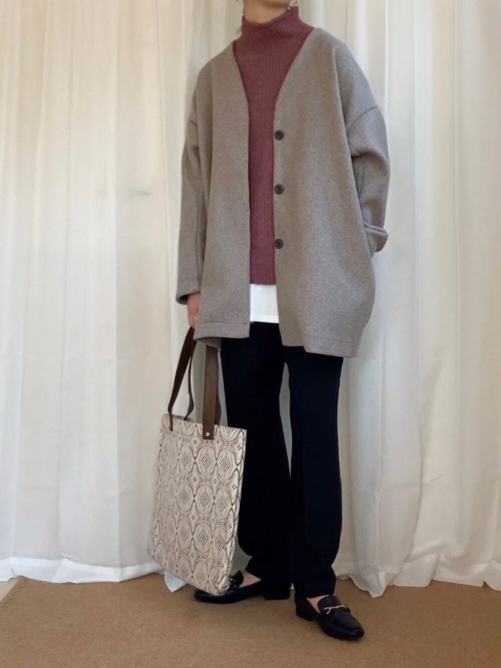 ベージュ系のノーカラーコート、ピンク系のニット/セーター、ベージュ系のトートバッグを着用したレディースの冬コーディネートの2枚目の写真