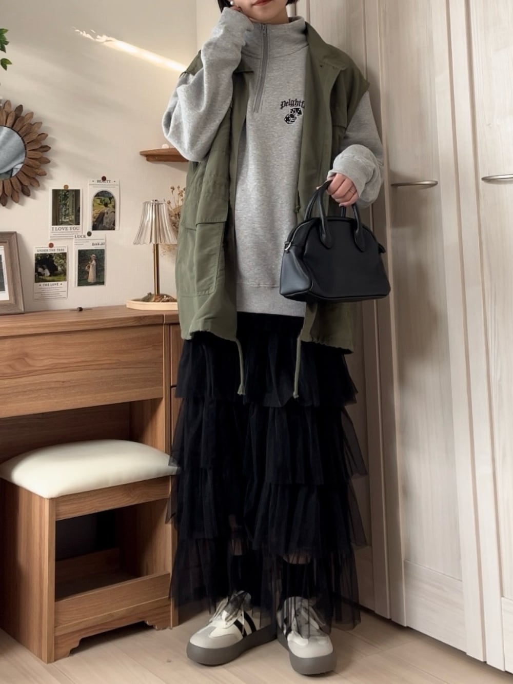 グレー系のスウェット、グリーン系のベスト、ブラック系のスカートを着用したレディースの春コーディネートの3枚目の写真