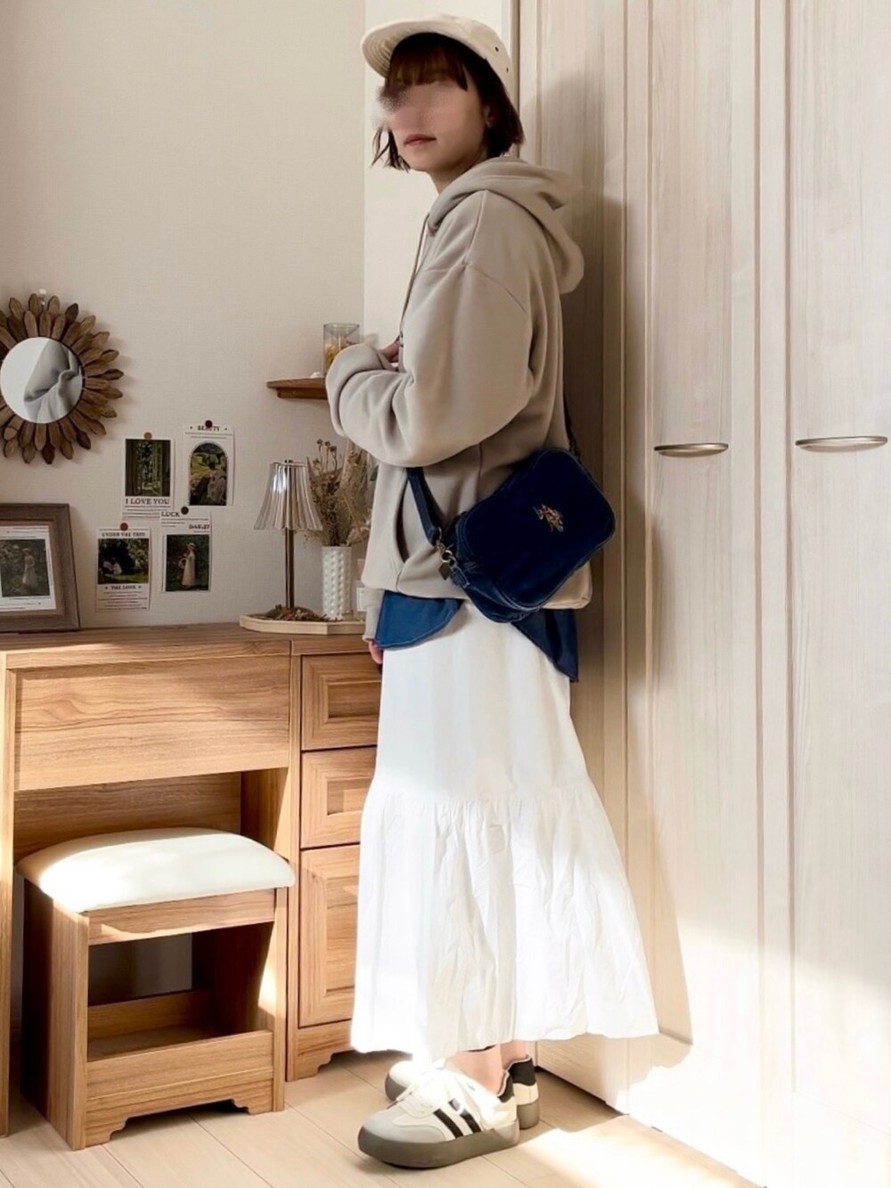 ベージュ系のパーカー、ホワイト系のスカート、ブルー系のショルダーバッグを着用したレディースの春コーディネートの2枚目の写真