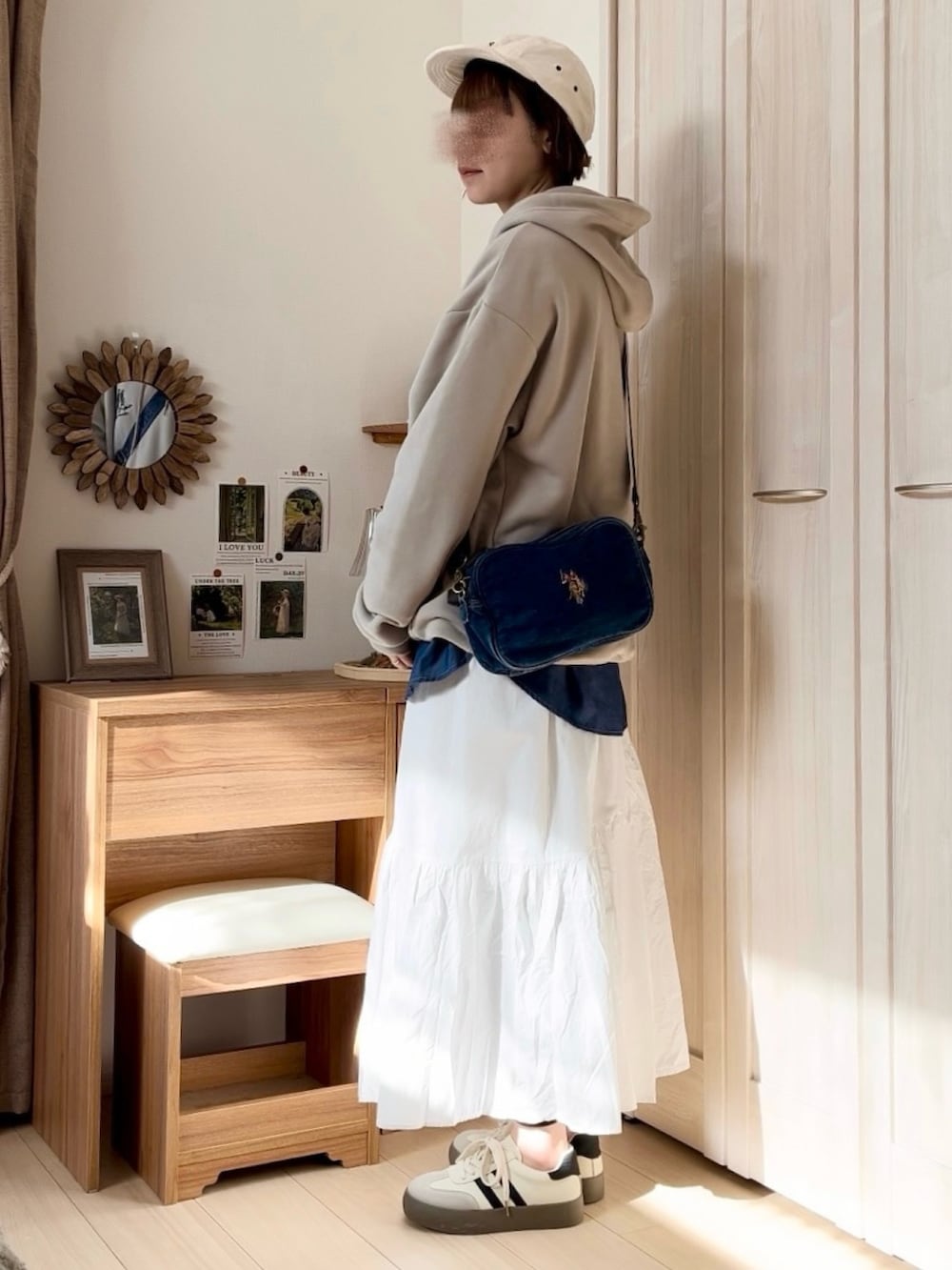 ベージュ系のパーカー、ホワイト系のスカート、ブルー系のショルダーバッグを着用したレディースの春コーディネートの3枚目の写真
