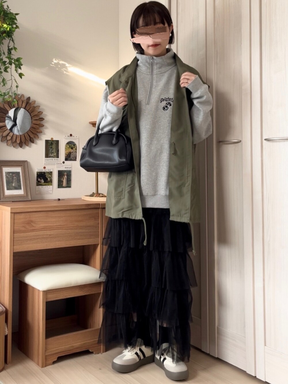 グレー系のスウェット、グリーン系のベスト、ブラック系のスカートを着用したレディースの春コーディネートの4枚目の写真