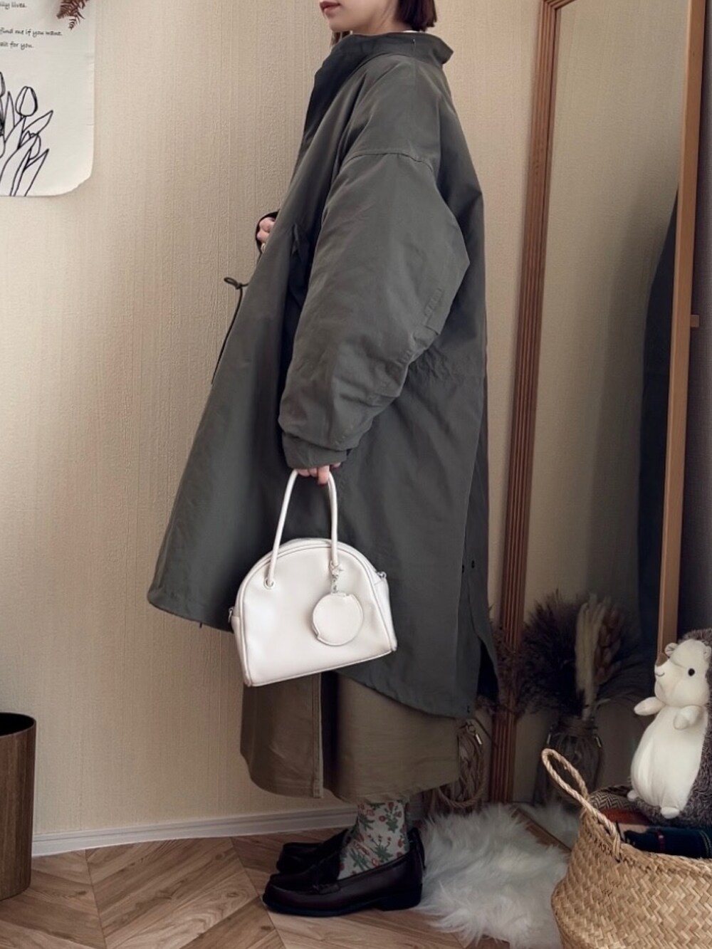 グリーン系のモッズコート、ブラウン系のカーディガン/ボレロ、ベージュ系のスカートを着用したレディースの冬コーディネートの3枚目の写真