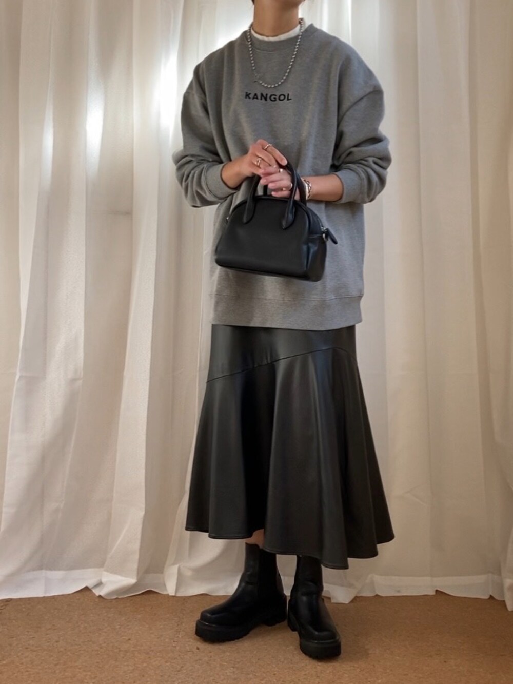 グレー系のスウェット、ブラック系のボストンバッグ、ブラック系のブーツを着用したレディースの冬コーディネートの2枚目の写真