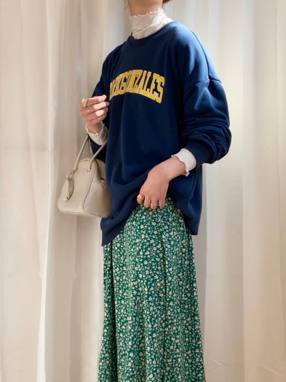 ブルー系のスウェット、グリーン系のスカート、ホワイト系のボストンバッグを着用したレディースの冬コーディネートの2枚目の写真