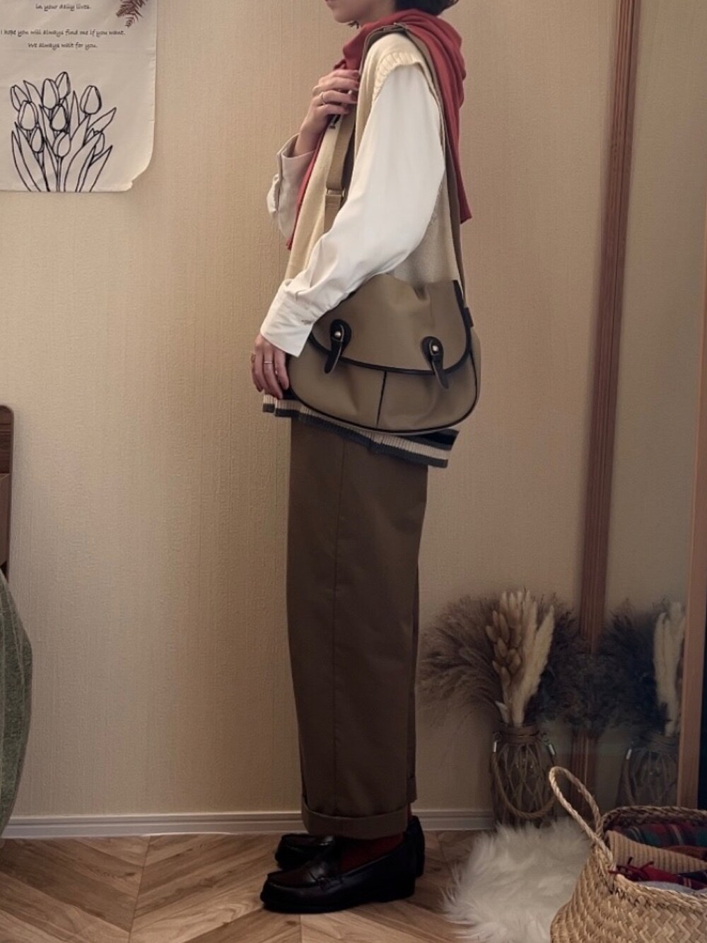 ホワイト系のベスト、グリーン系のチノパンツ、ベージュ系のショルダーバッグを着用したレディースの冬コーディネートの4枚目の写真