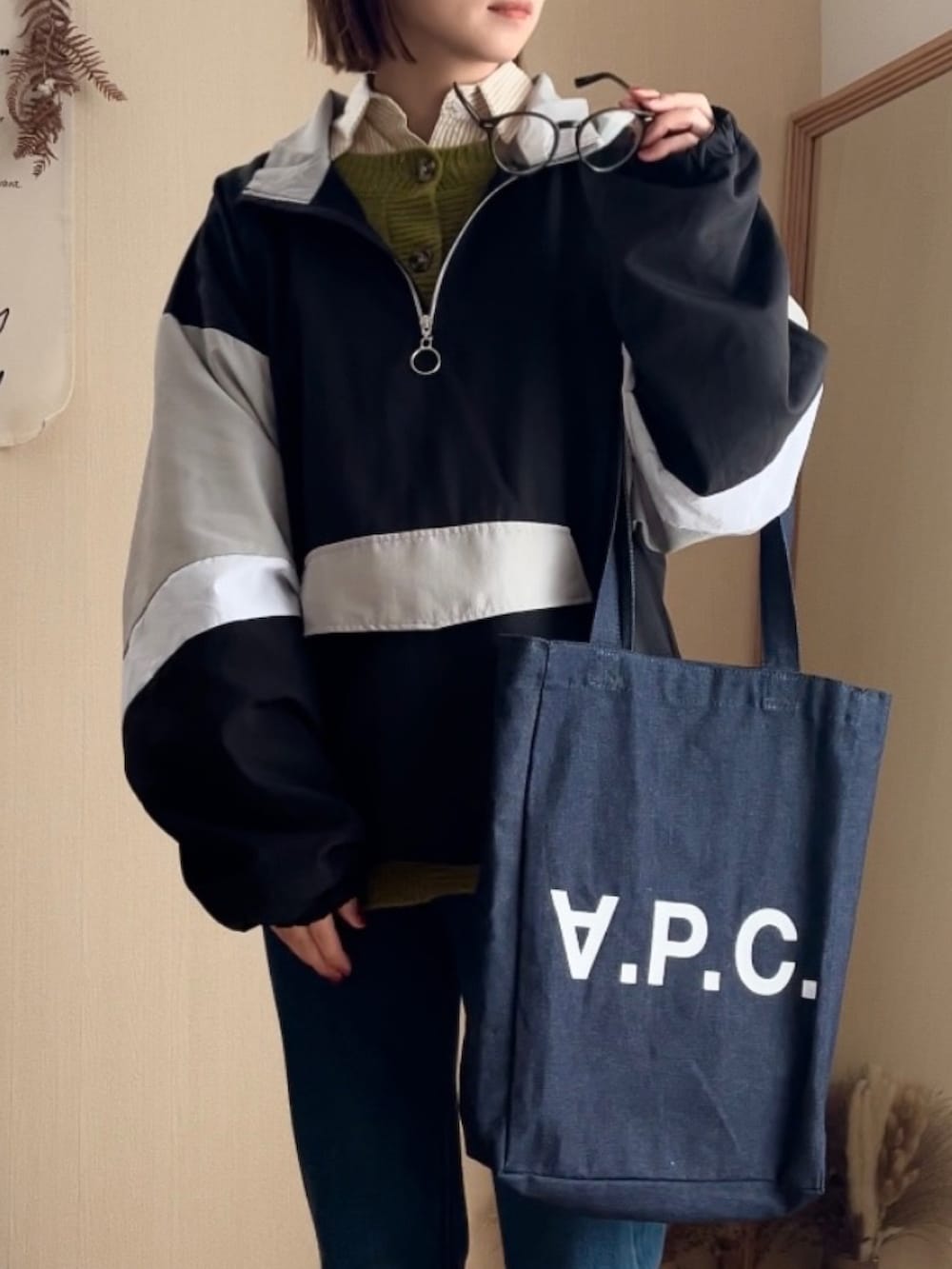 ブラック系のナイロンジャケット、グリーン系のカーディガン/ボレロ、ブルー系のデニムパンツを着用したレディースの冬コーディネートの2枚目の写真