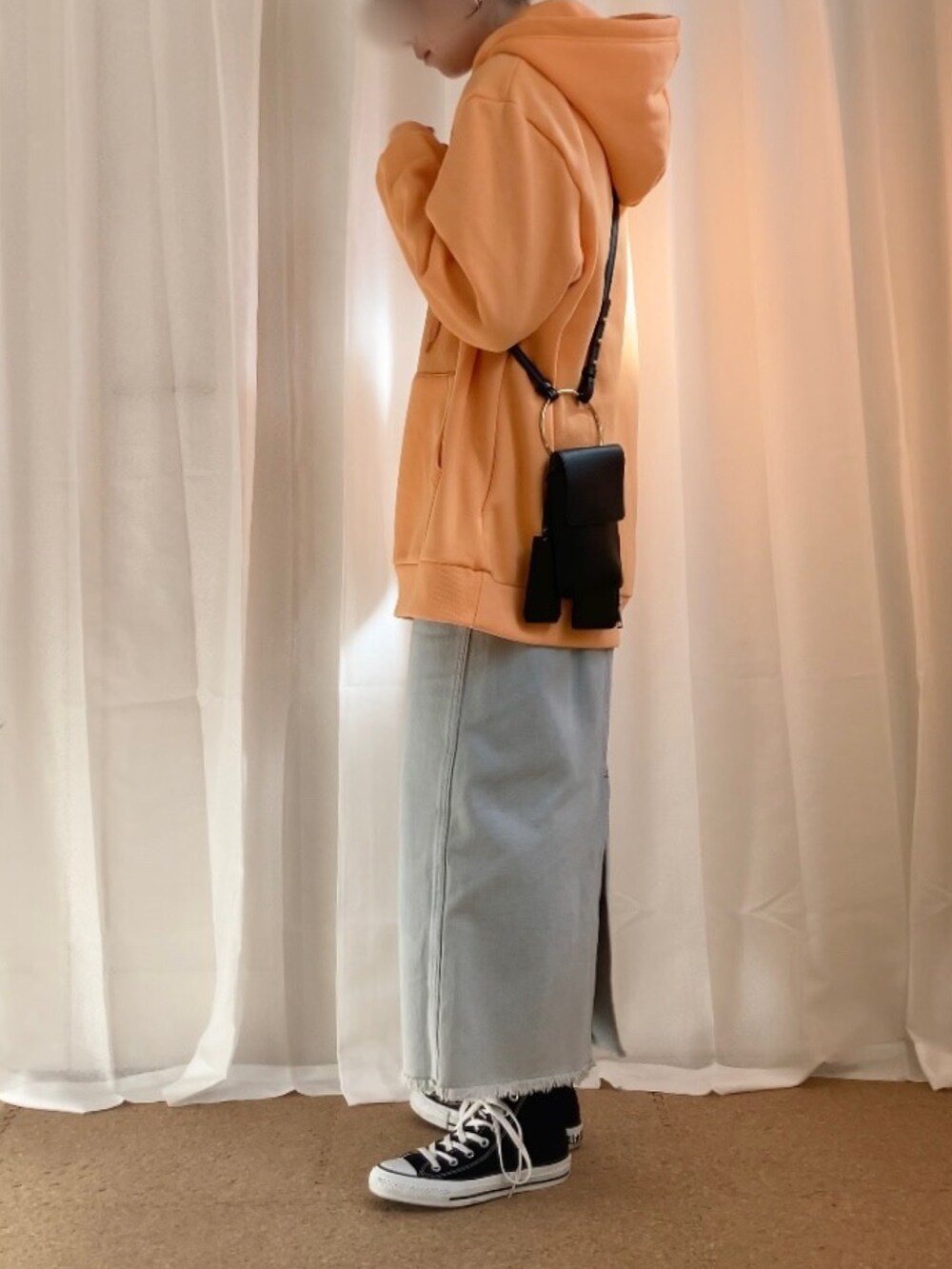 オレンジ系のパーカー、ブルー系のスカート、ブラック系のショルダーバッグを着用したレディースの春コーディネートの2枚目の写真