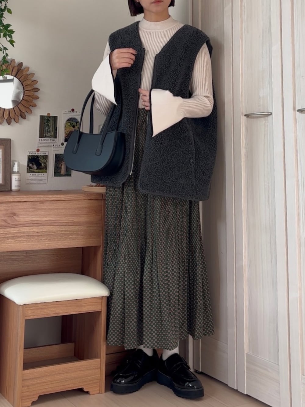 グリーン系のスカート、ホワイト系のニット/セーター、グレー系のベストを着用したレディースの冬コーディネートの3枚目の写真