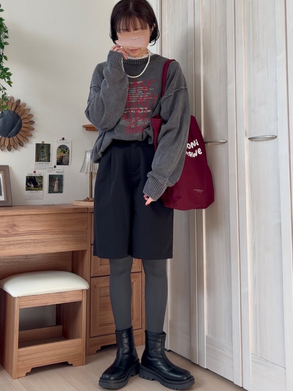 ブラック系のニット/セーター、ブラック系のチノパンツ、レッド系のトートバッグを着用したレディースの冬コーディネートの2枚目の写真