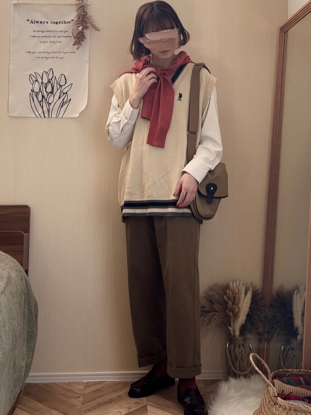 ホワイト系のベスト、グリーン系のチノパンツ、ベージュ系のショルダーバッグを着用したレディースの冬コーディネートの3枚目の写真