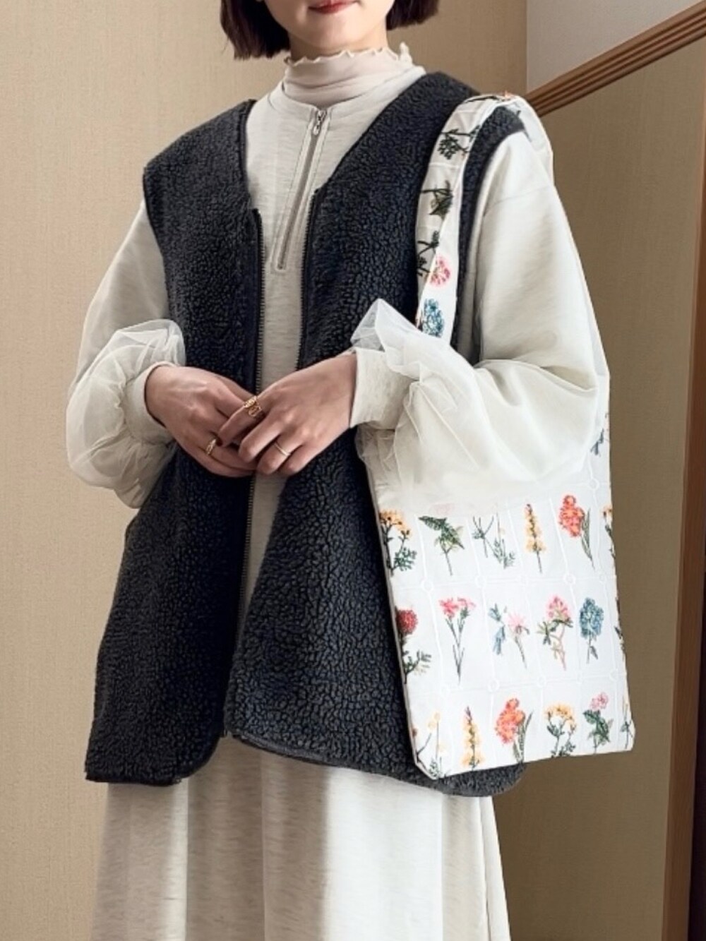 グレー系のワンピース、グレー系のベスト、ブラウン系のブーツを着用したレディースの冬コーディネートの2枚目の写真