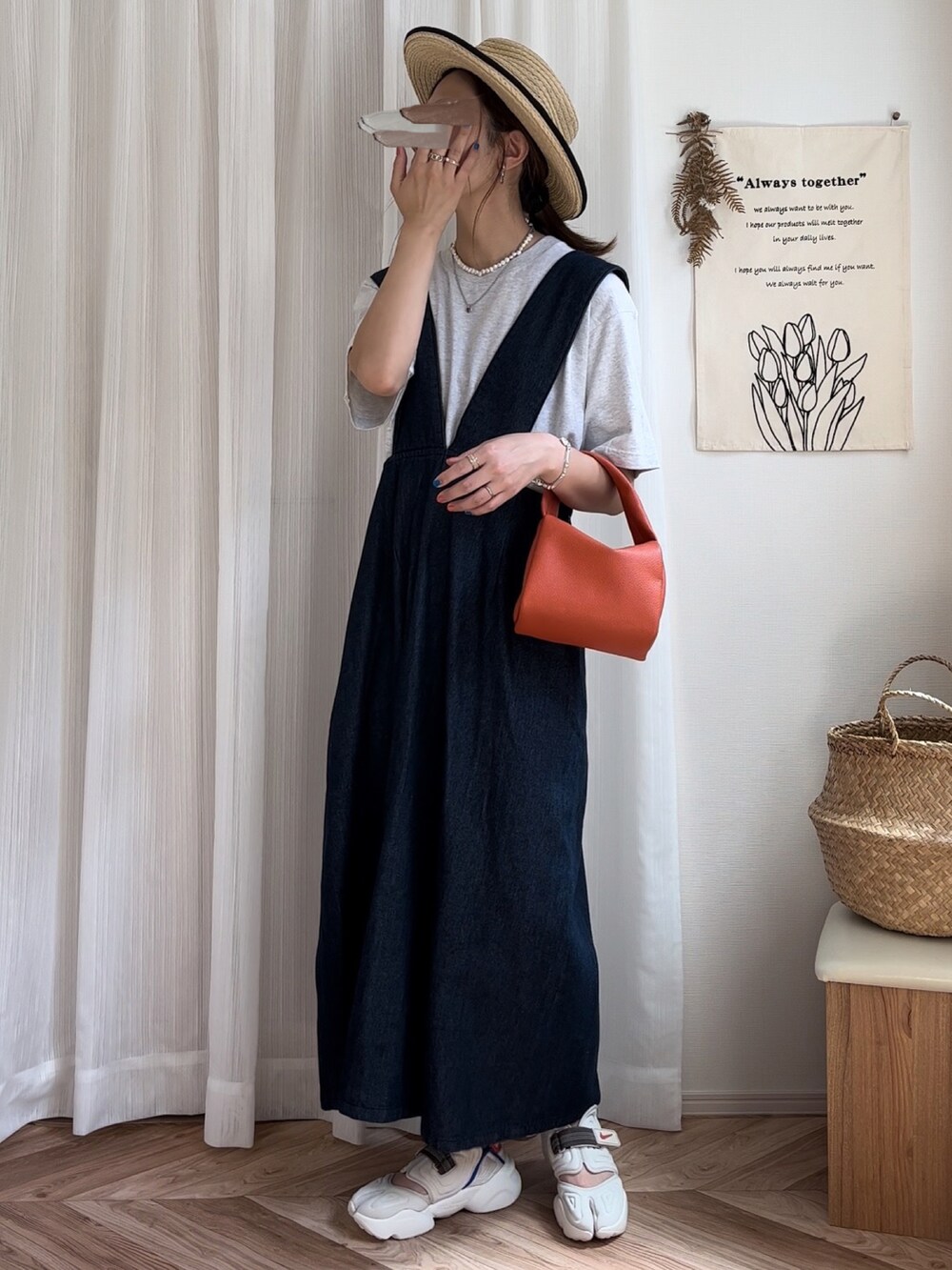 ベージュ系のTシャツ/カットソー、ブルー系のジャンパースカート、オレンジ系のハンドバッグを着用したレディースの夏コーディネートの3枚目の写真