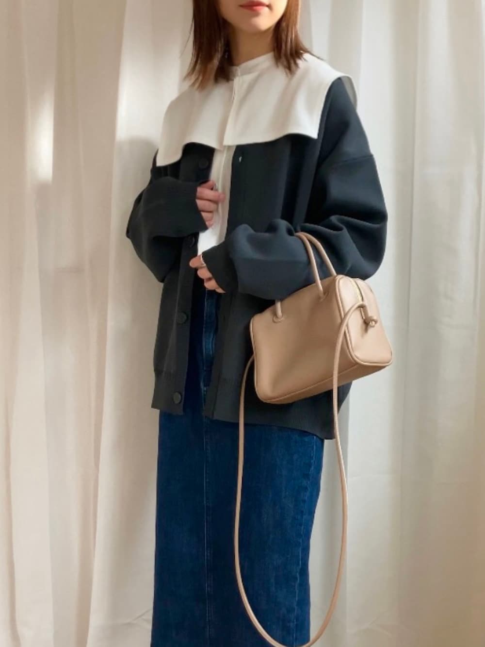 グレー系のカーディガン/ボレロ、ホワイト系のシャツ/ブラウス、ブルー系のデニムスカートを着用したレディースの冬コーディネートの2枚目の写真