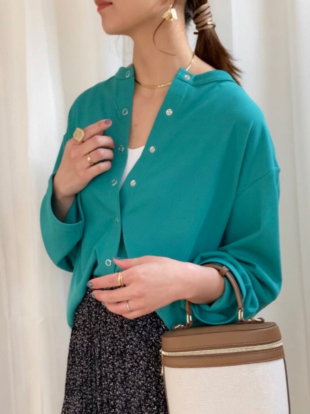 グリーン系のカーディガン/ボレロ、ブラウン系のパンプス、ゴールド系のネックレスを着用したレディースの春コーディネートの2枚目の写真