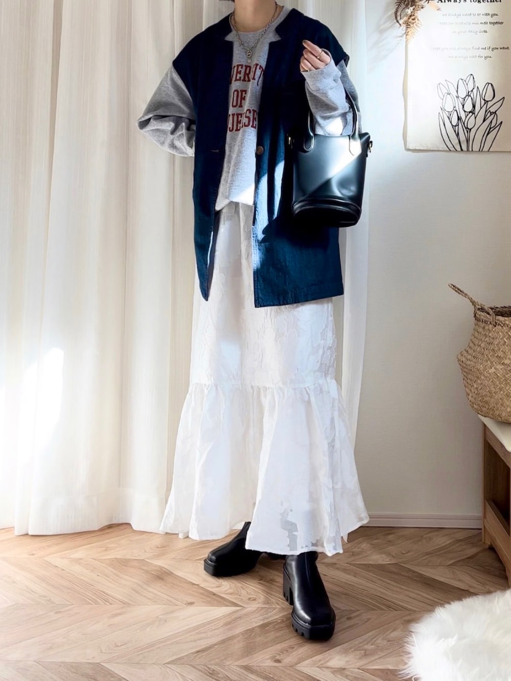 グレー系のスウェット、ホワイト系のスカート、ブルー系のベストを着用したレディースの秋コーディネートの2枚目の写真